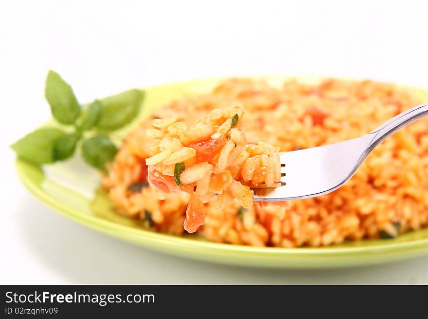 Risotto with tomatoes on a green plate decorated with basil - some of it on a fork