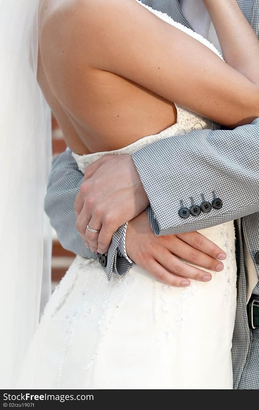 Man's hands embrace the bride in a beautiful dress. Man's hands embrace the bride in a beautiful dress