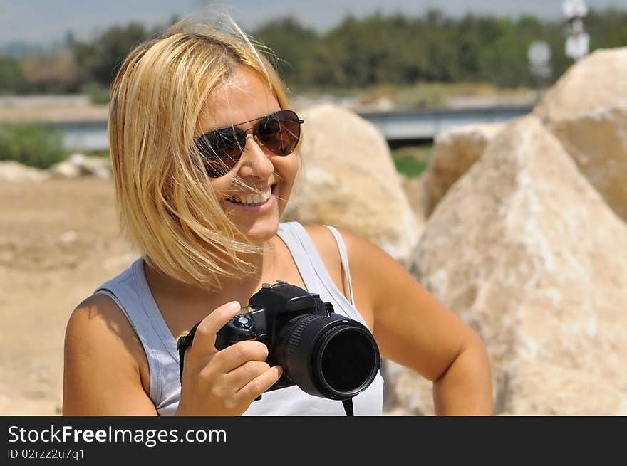 Blonde woman in sunglasses with a camera.