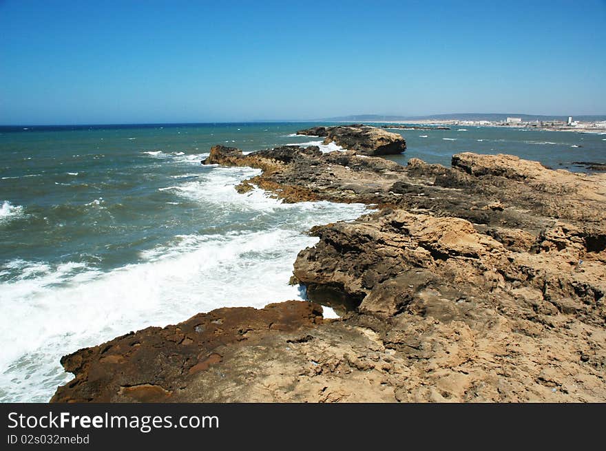 Sea waves hitting cliffs, blue sky