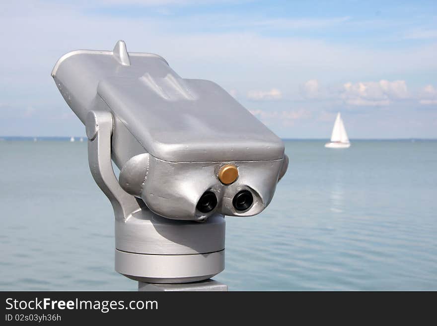 Telescope on the coast. Sailing boats show on the lake in the background. Telescope on the coast. Sailing boats show on the lake in the background.