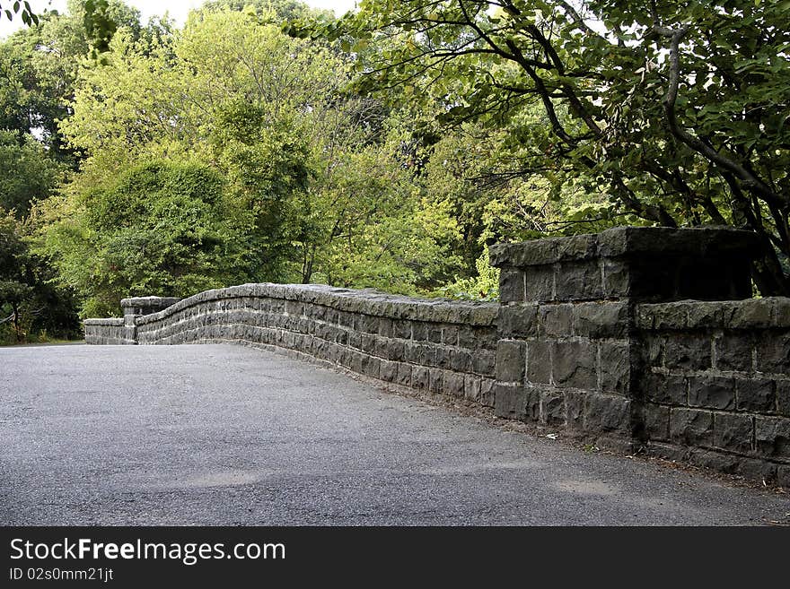 Path leads to stone bridge in a quiet and calm park setting. Path leads to stone bridge in a quiet and calm park setting