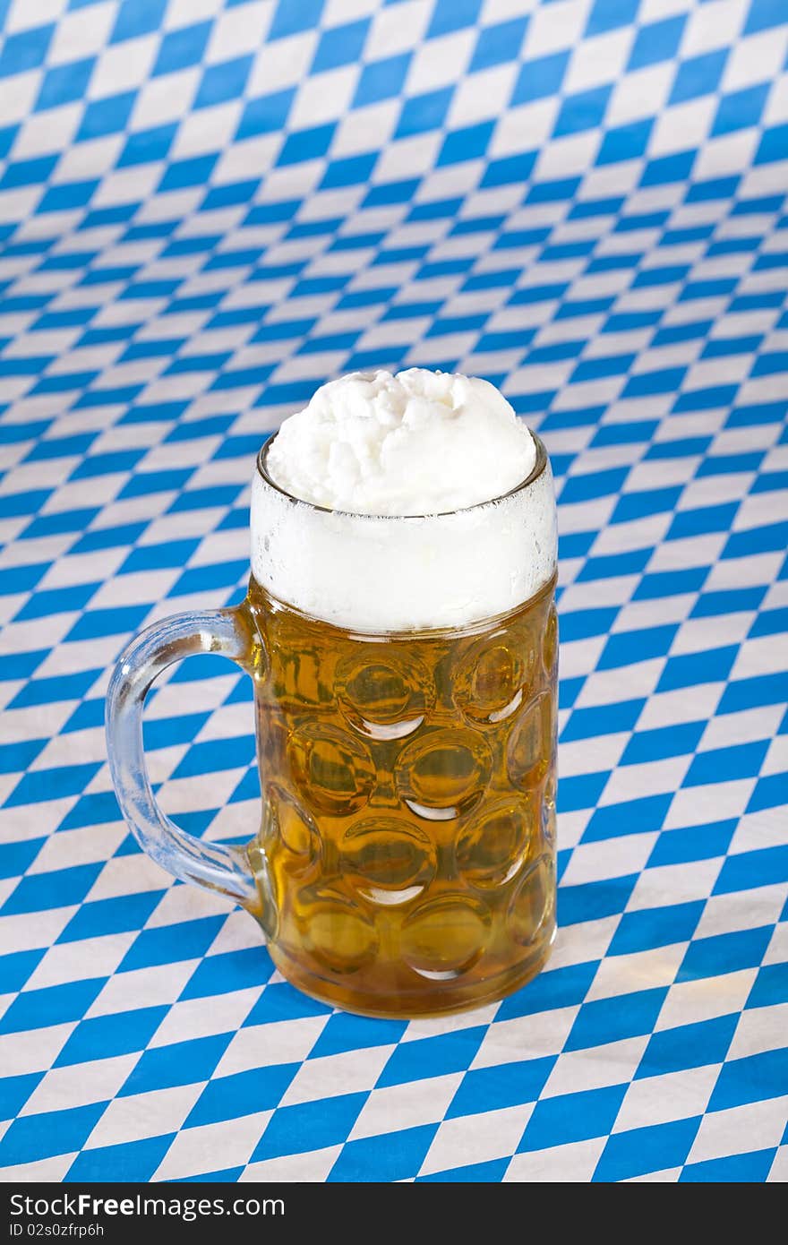 Oktoberfest beer stein and Bavarian flag in background. Oktoberfest beer stein and Bavarian flag in background.