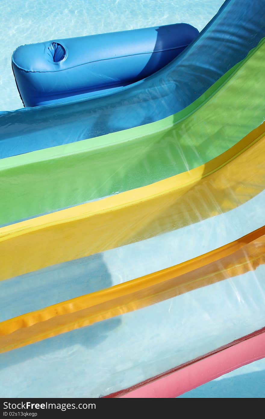 A close up of an inflatable rainbow colored chair in a swimming pool. A close up of an inflatable rainbow colored chair in a swimming pool