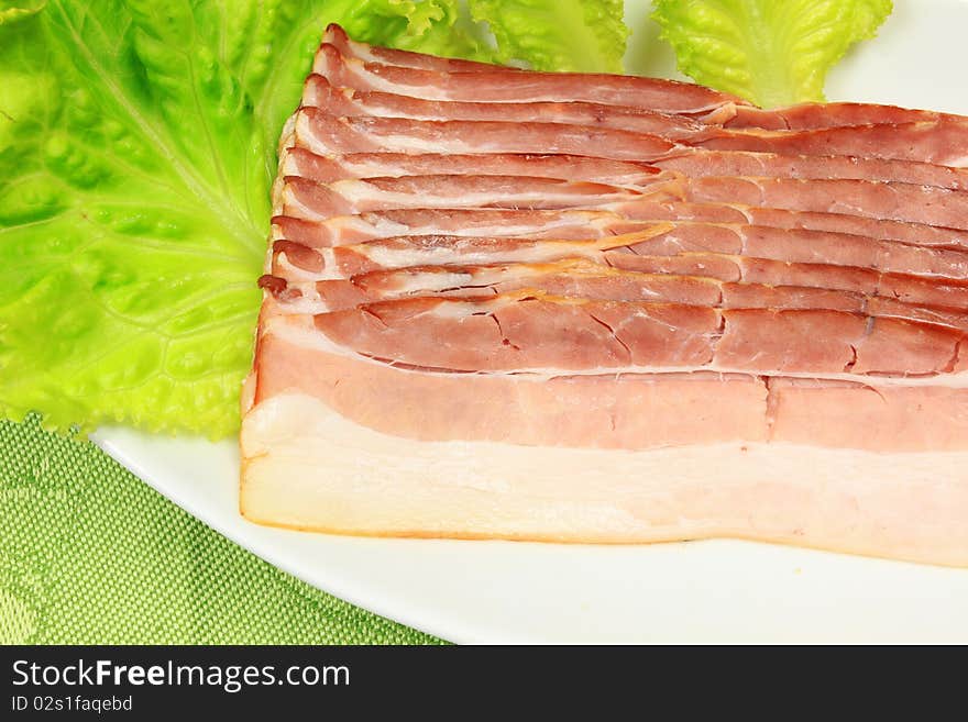 Slices of fresh bacon on white plate