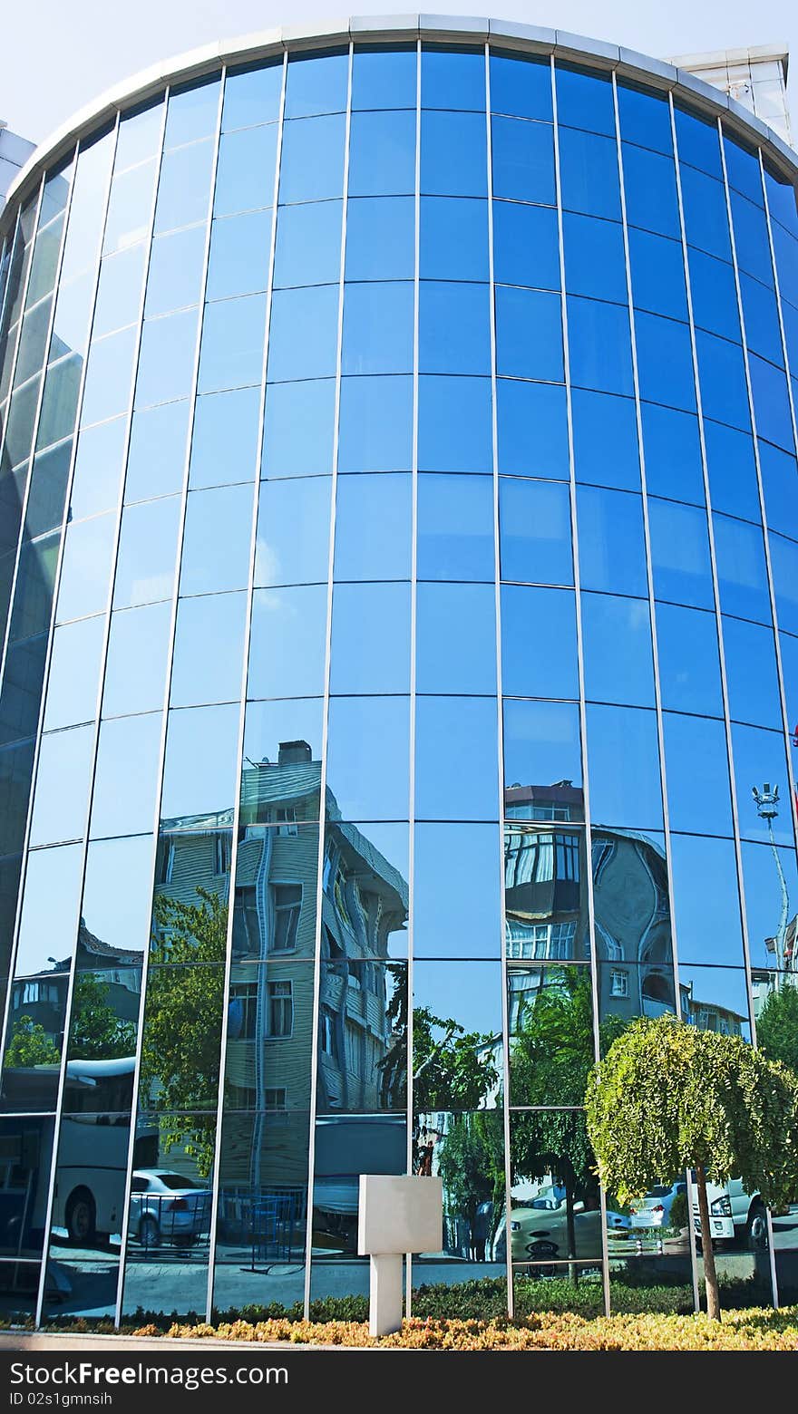 Front of a curved glass building with abstract reflections in the window. Front of a curved glass building with abstract reflections in the window