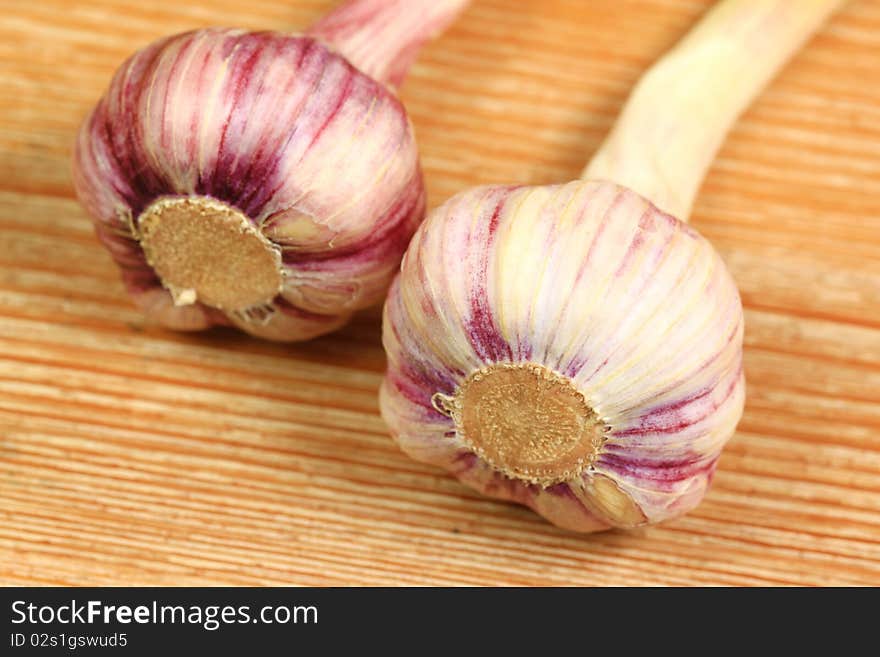 Whole violet garlic heads on wooden board. Whole violet garlic heads on wooden board