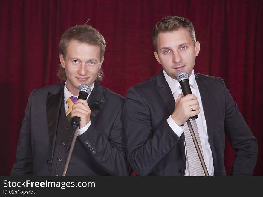 Two male entertainers with microphones on the stage. Two male entertainers with microphones on the stage