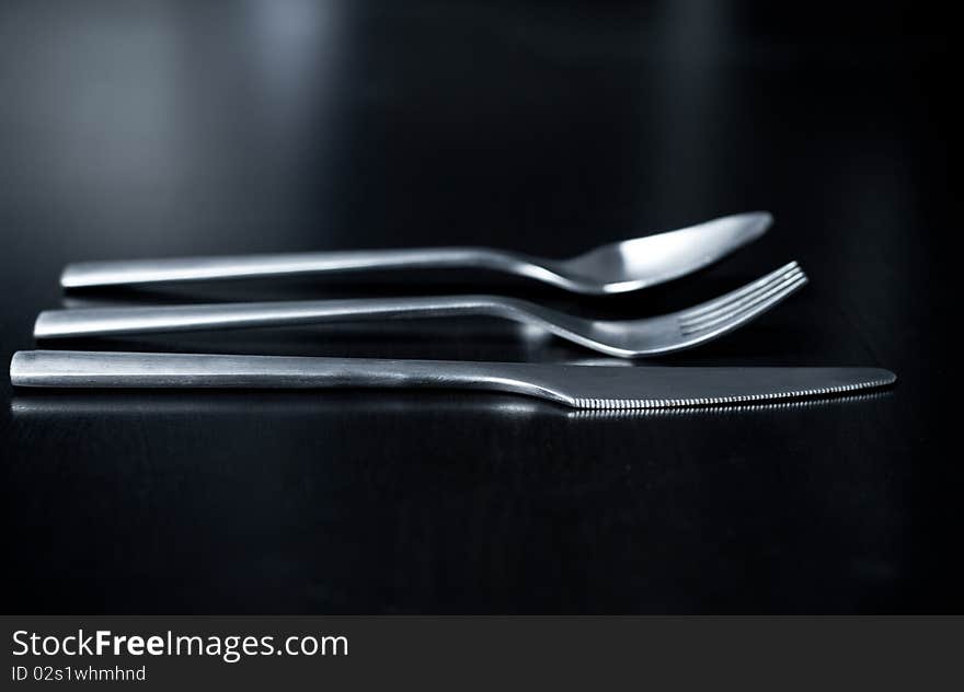 Silverware on black table (shallow DOF, focus on fork)