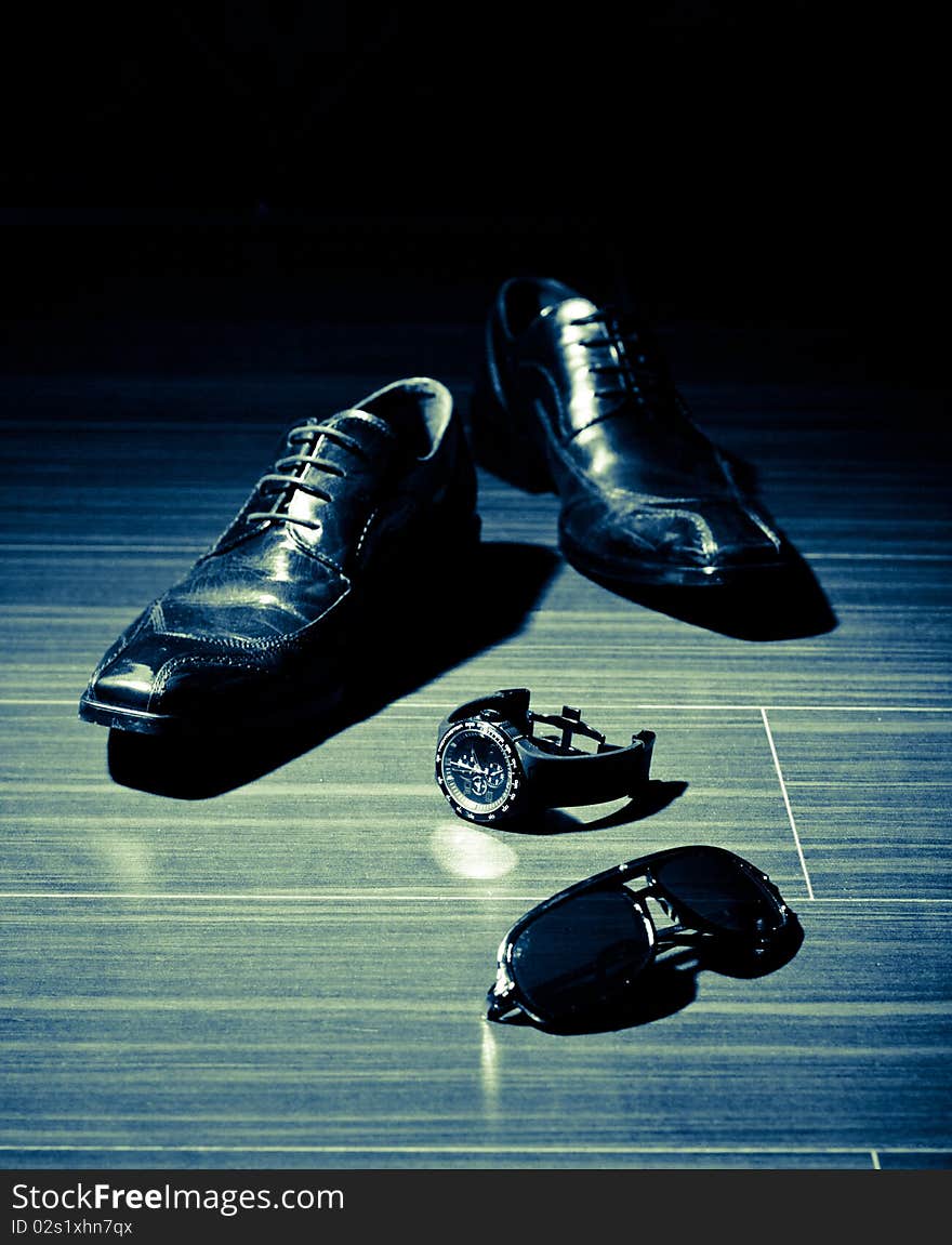 Dress shoes and a watch in the spotlight (focus on watch)