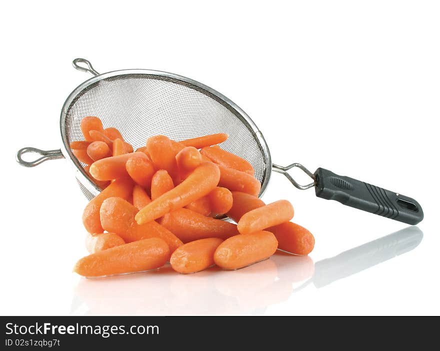 Freshly washed baby carrots spill from a kitchen strainer. Freshly washed baby carrots spill from a kitchen strainer