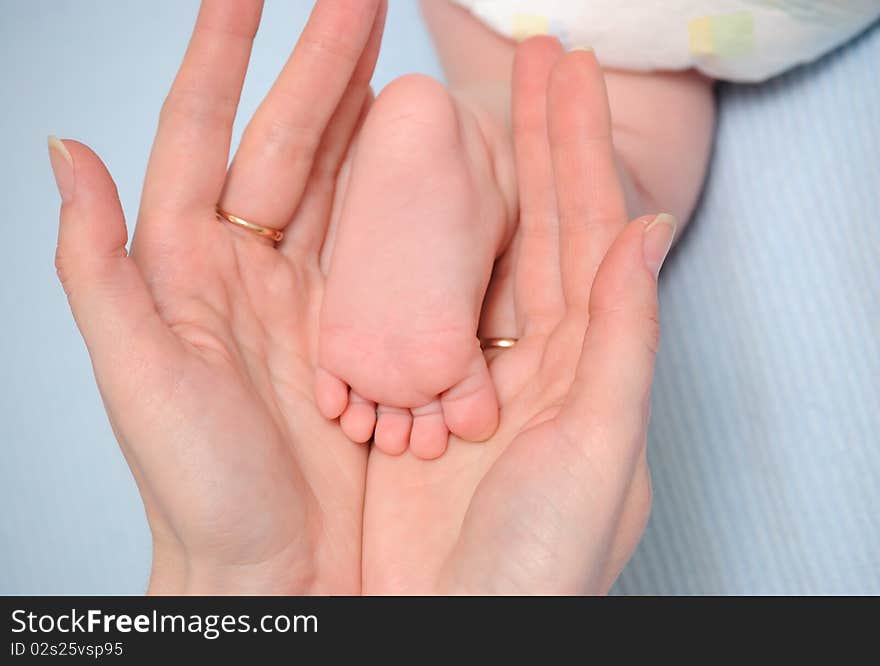 Mum holds a foot of the child in hands. Mum holds a foot of the child in hands