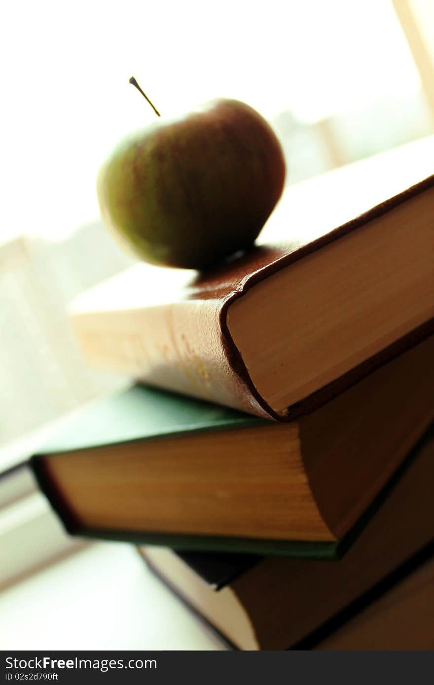 Stack of old books books with an apple. on a background window. Stack of old books books with an apple. on a background window