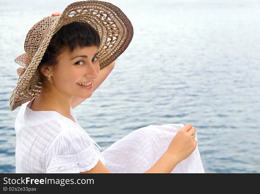 Happy young girl in the bonnet near the sea