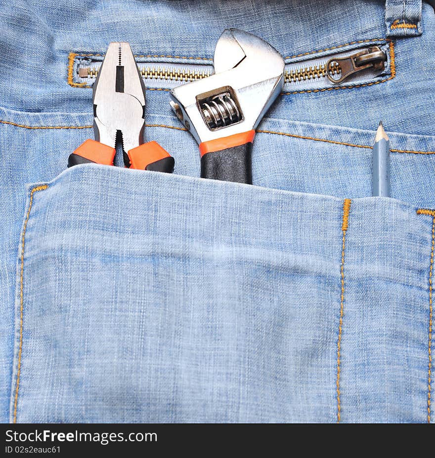 Adjustable wrench and pliers in blue jeans pocket. Adjustable wrench and pliers in blue jeans pocket