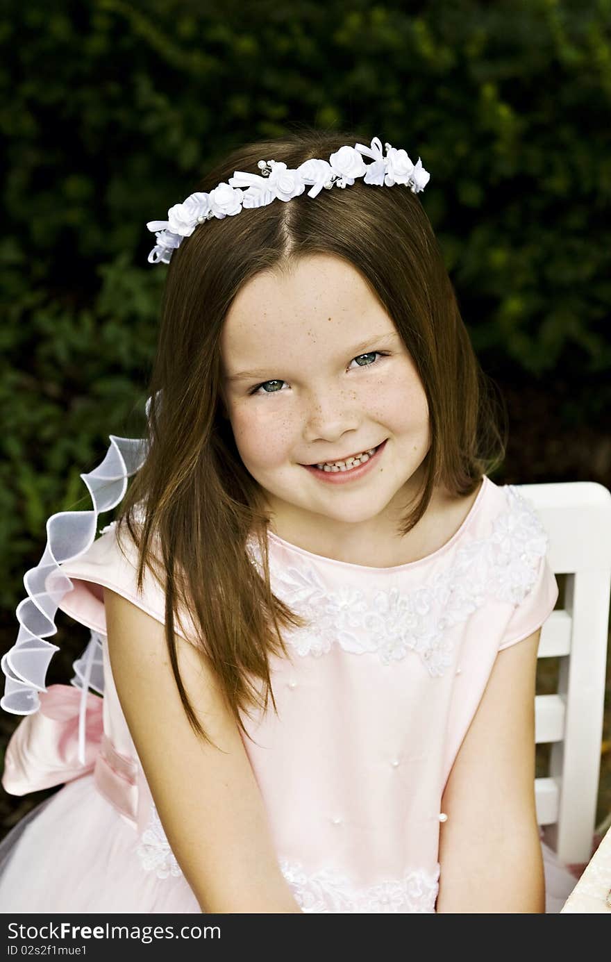 A smiling little six year old girl in a pretty pink dress, closeup with selective focus. A smiling little six year old girl in a pretty pink dress, closeup with selective focus