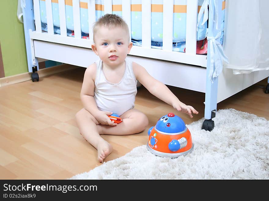 Little baby boy (1 year old) sitting on floor at children's room and playing with toys. Little baby boy (1 year old) sitting on floor at children's room and playing with toys