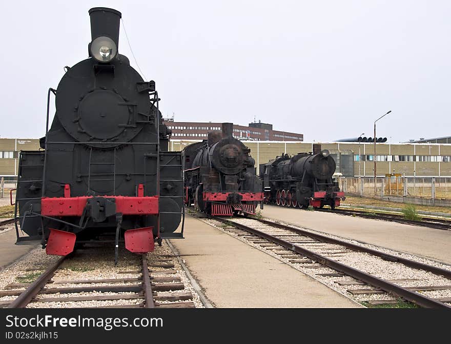 Steam locomotives beside a railway station platform. Retro train.