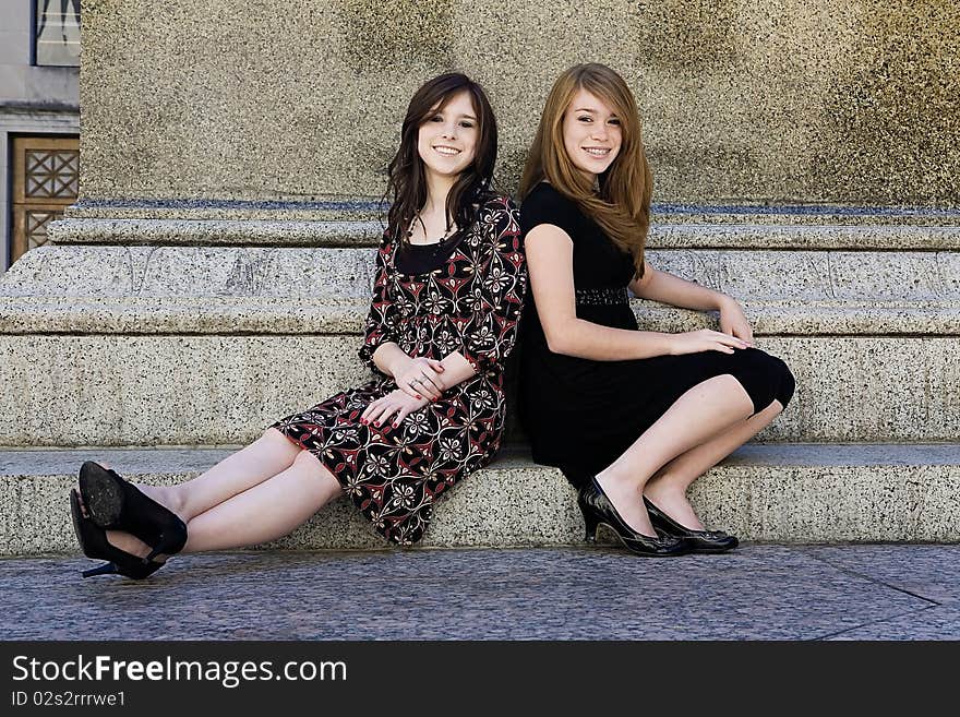 Two young girls sitting downtown