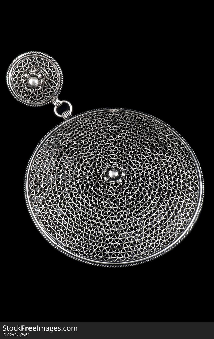 A decorative circular silver pendent isolated on a black background