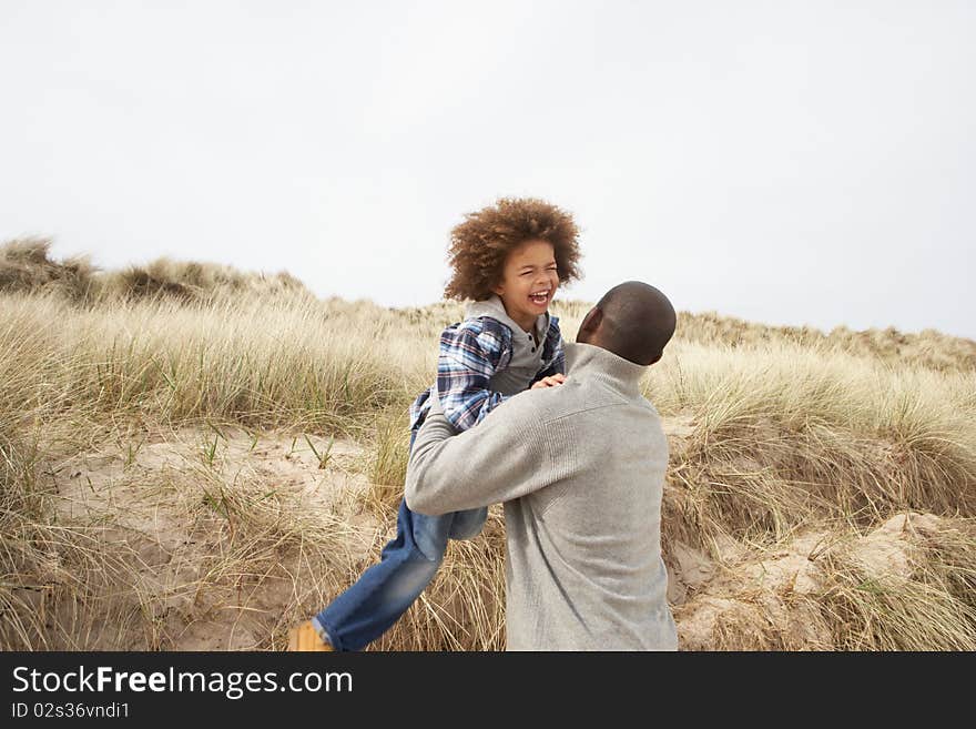 Father And Son Having Fun In Sand Dunes