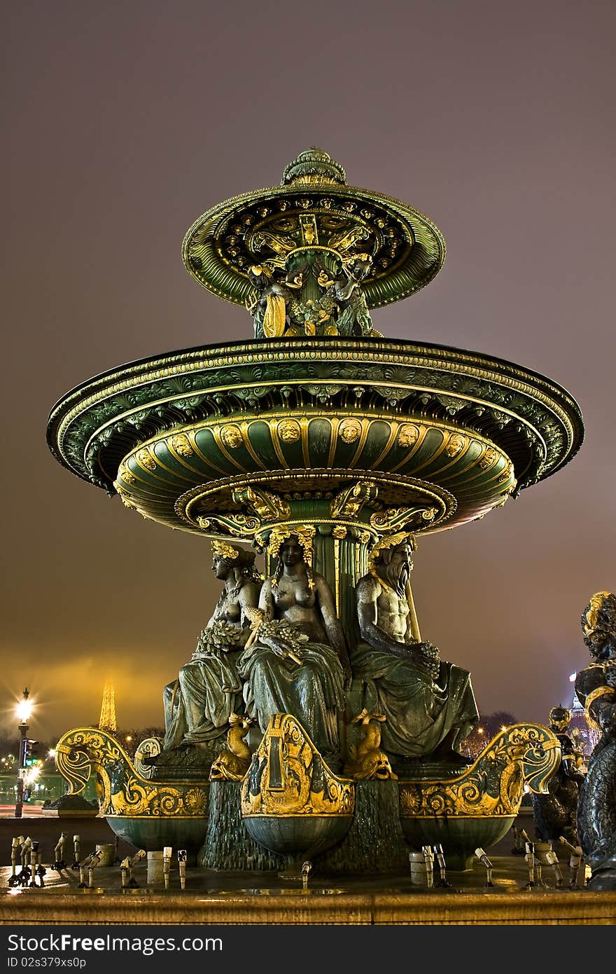 Fountain at Place de la Concorde with Eiffel Tower in the background on a cloudy night. Fountain at Place de la Concorde with Eiffel Tower in the background on a cloudy night.