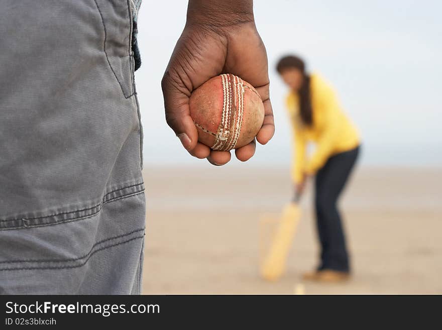 Young Couple Playing Cricket On Autumn Beach Holiday in the sun