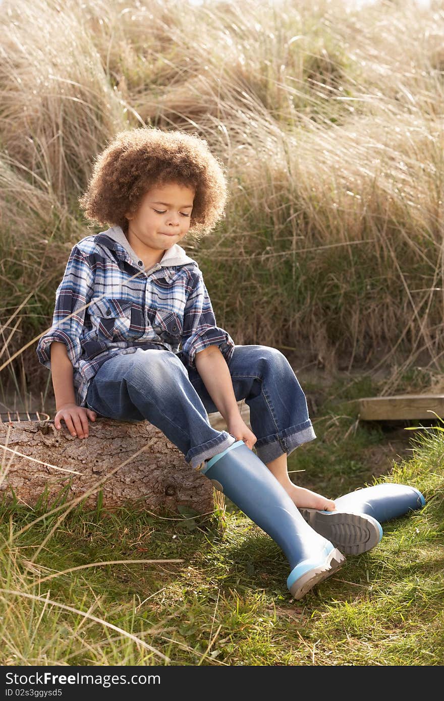 Young Boy Putting On Wellington Boots