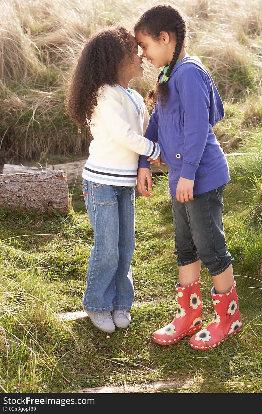 Young Girls Playing In Field Together in the sun