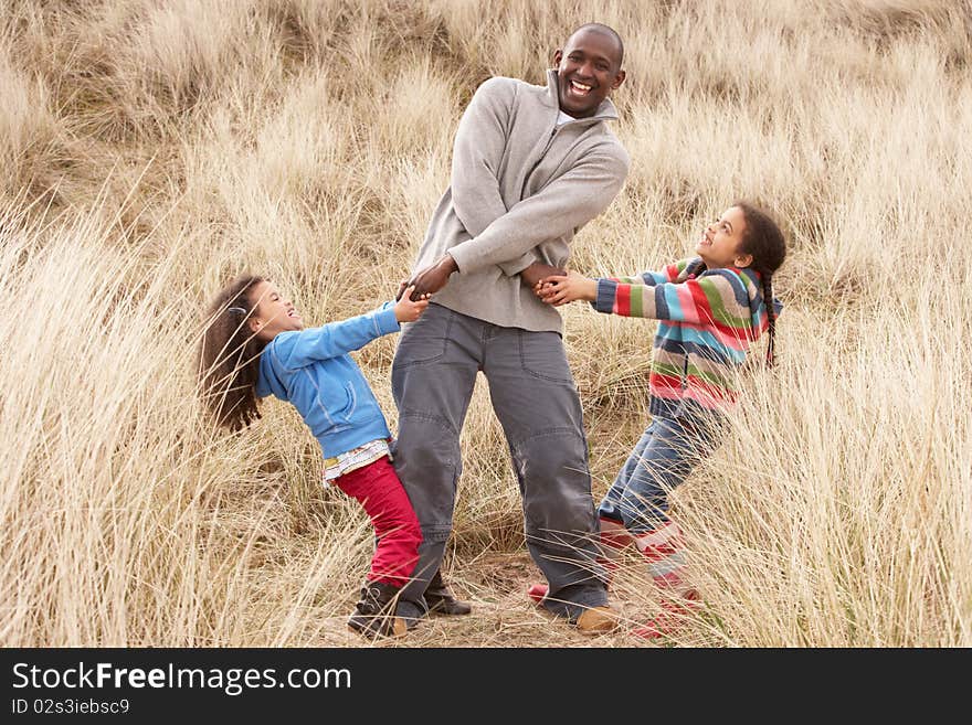 Father And Daughters Having Fun In Sand Dunes in the sun