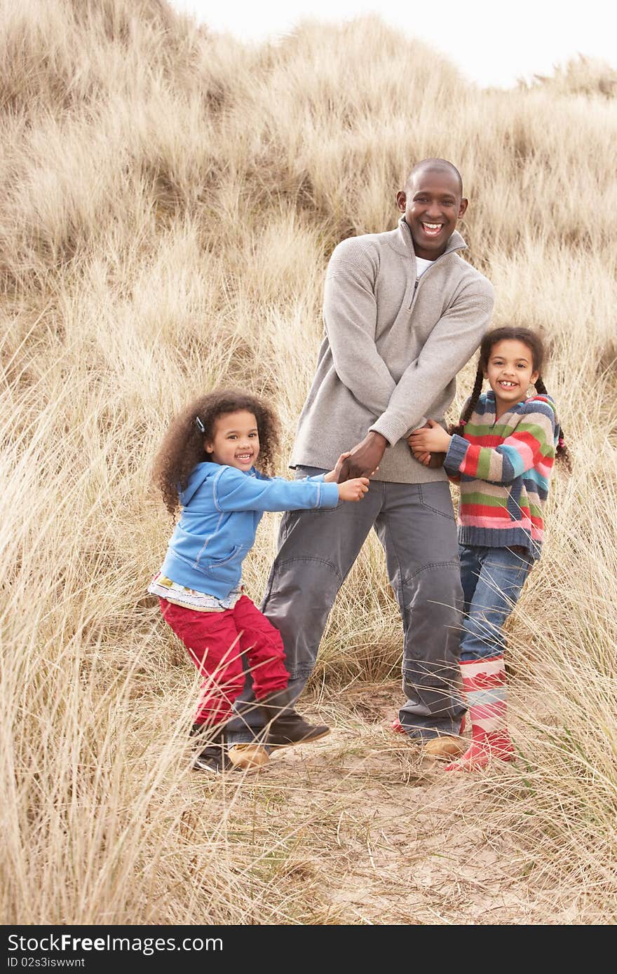 Father And Daughters Having Fun In Sand Dunes in the sun