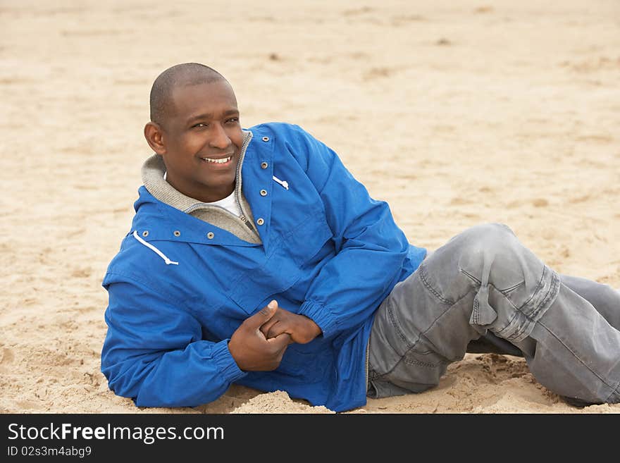 Man Relaxing On Beach In Autumn Clothing in the sun