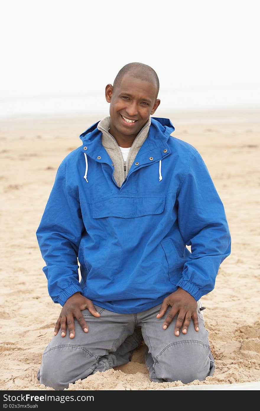 Man Relaxing On Beach In Autumn Clothing in the sun