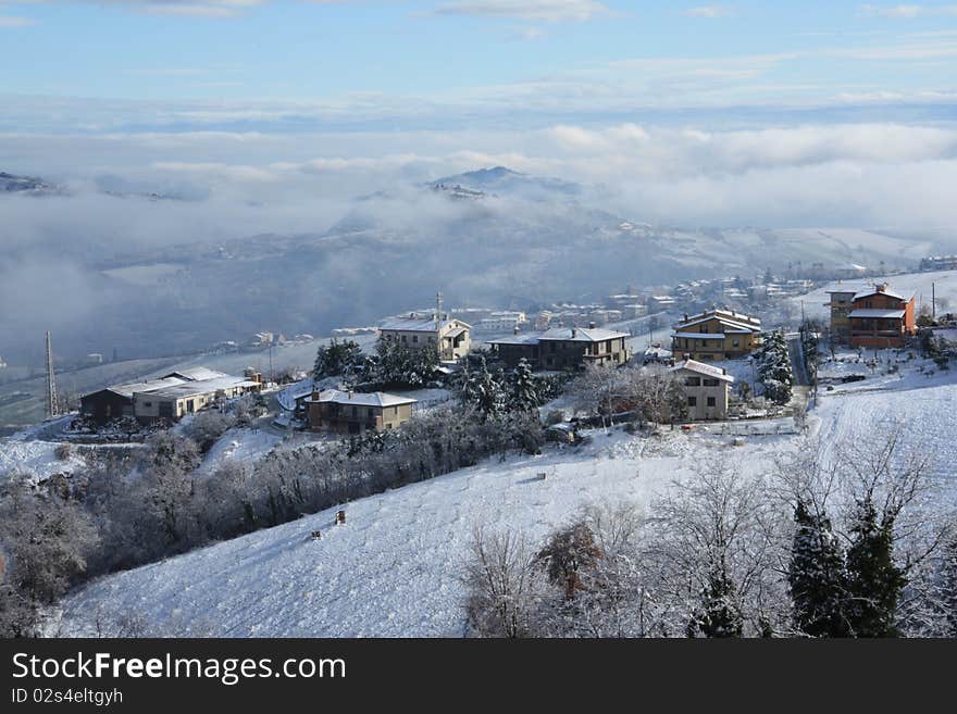 Snow on the houses, clouds under hte mountain