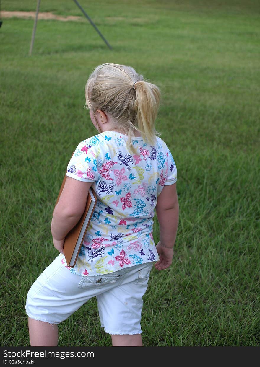 Little girl on playground holding a book. Little girl on playground holding a book.