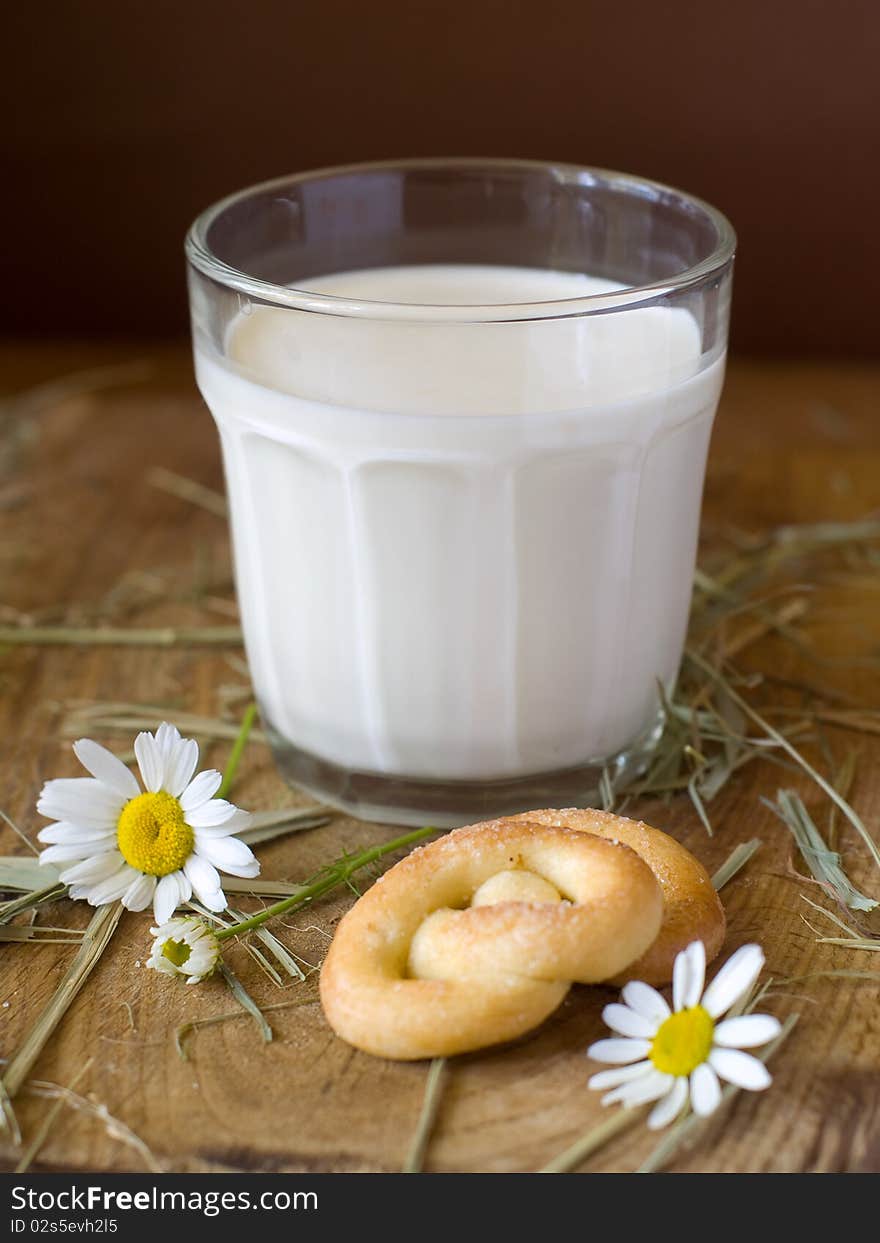 Glass of milk on a board with two cookies and chamomile