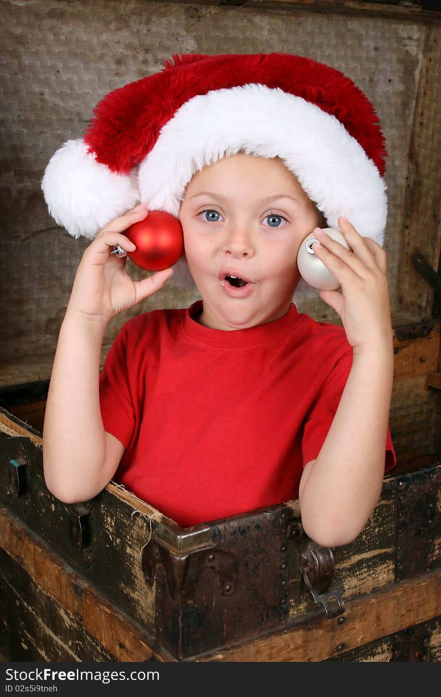 Young boy wearing a Christmas hat, sitting inside a trunk. Young boy wearing a Christmas hat, sitting inside a trunk