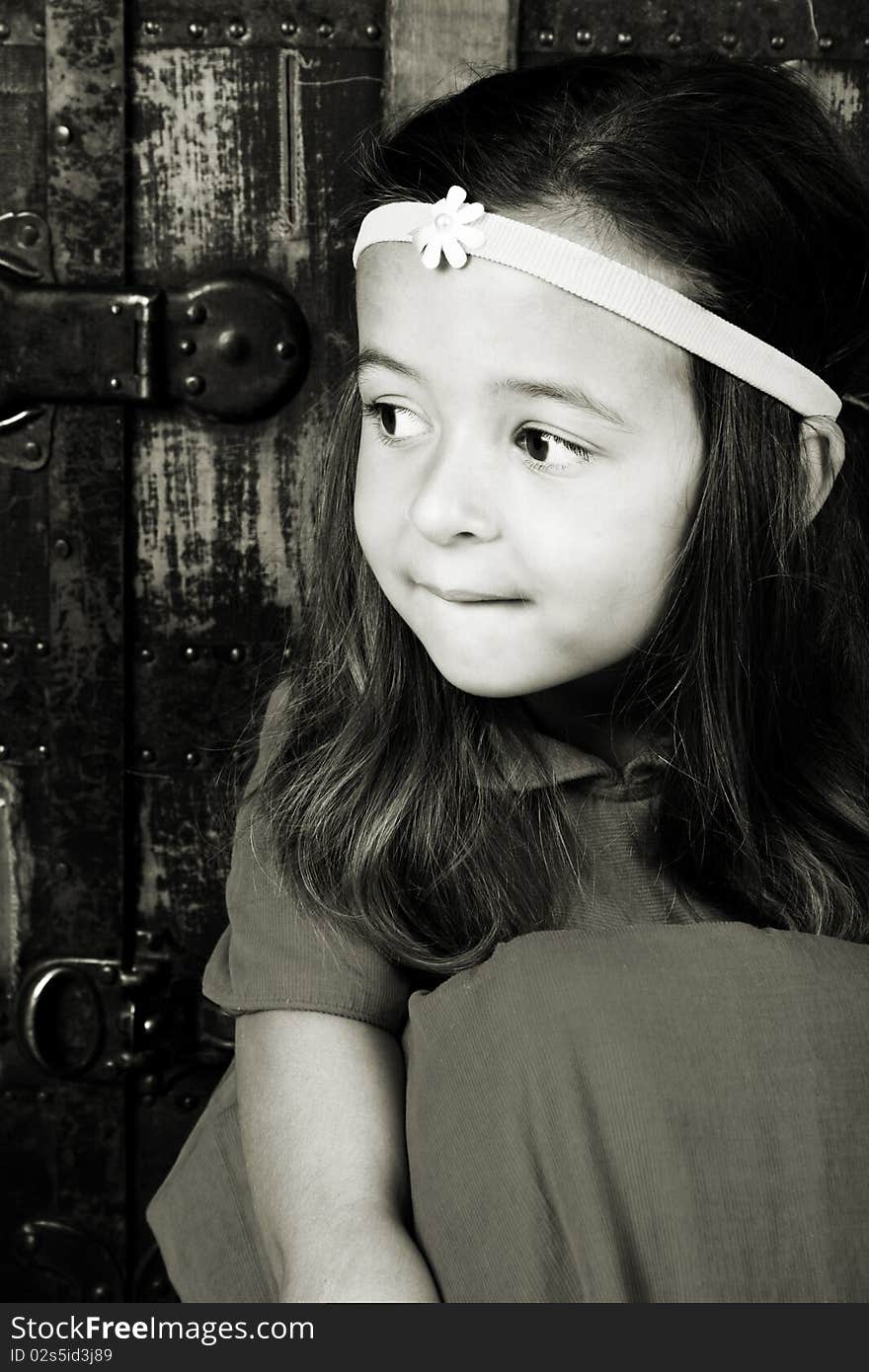 Cute brunette girl sitting against an antique trunk wearing a headband. Cute brunette girl sitting against an antique trunk wearing a headband