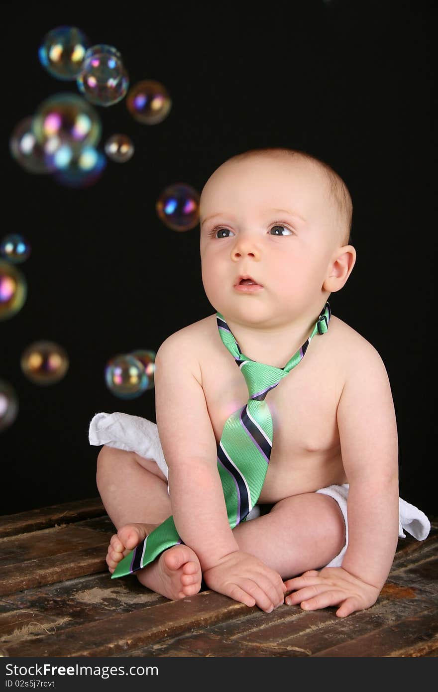 Cute baby boy sitting on an antique trunk looking at bubbles. Cute baby boy sitting on an antique trunk looking at bubbles