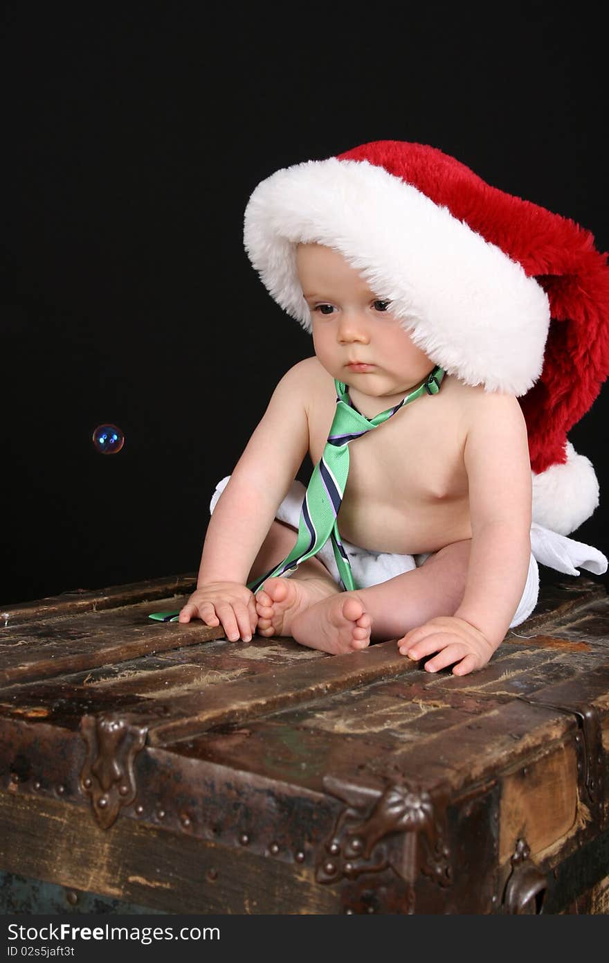 Cute christmas baby boy sitting on an antique trunk