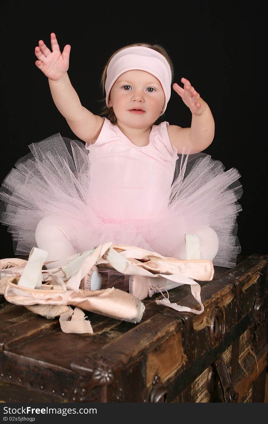 Baby ballerina sitting on an antique trunk. Baby ballerina sitting on an antique trunk