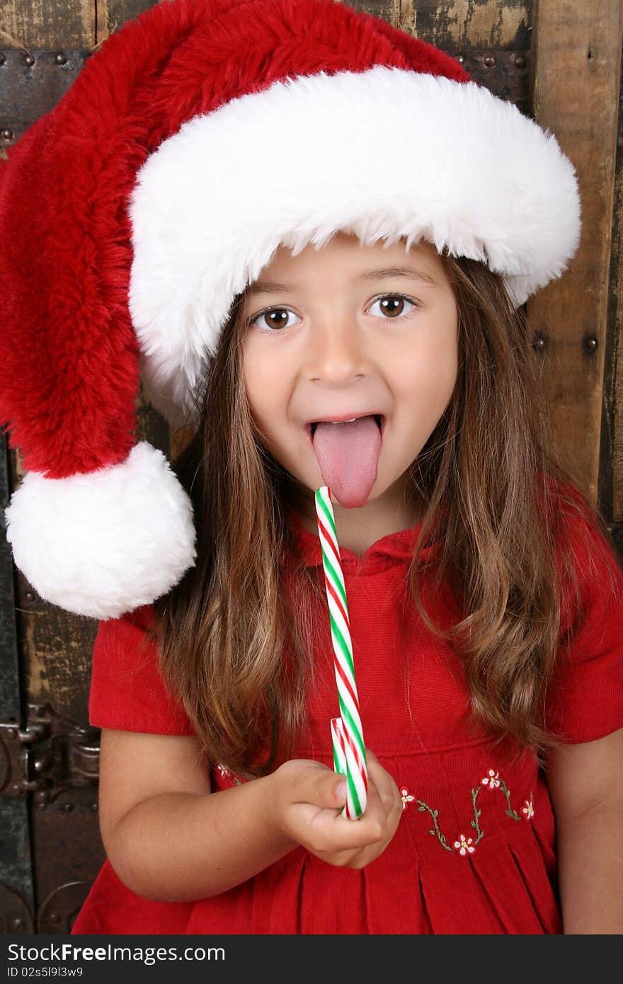 Cute brunette girl eating Christmas candy and sticking her tongue out