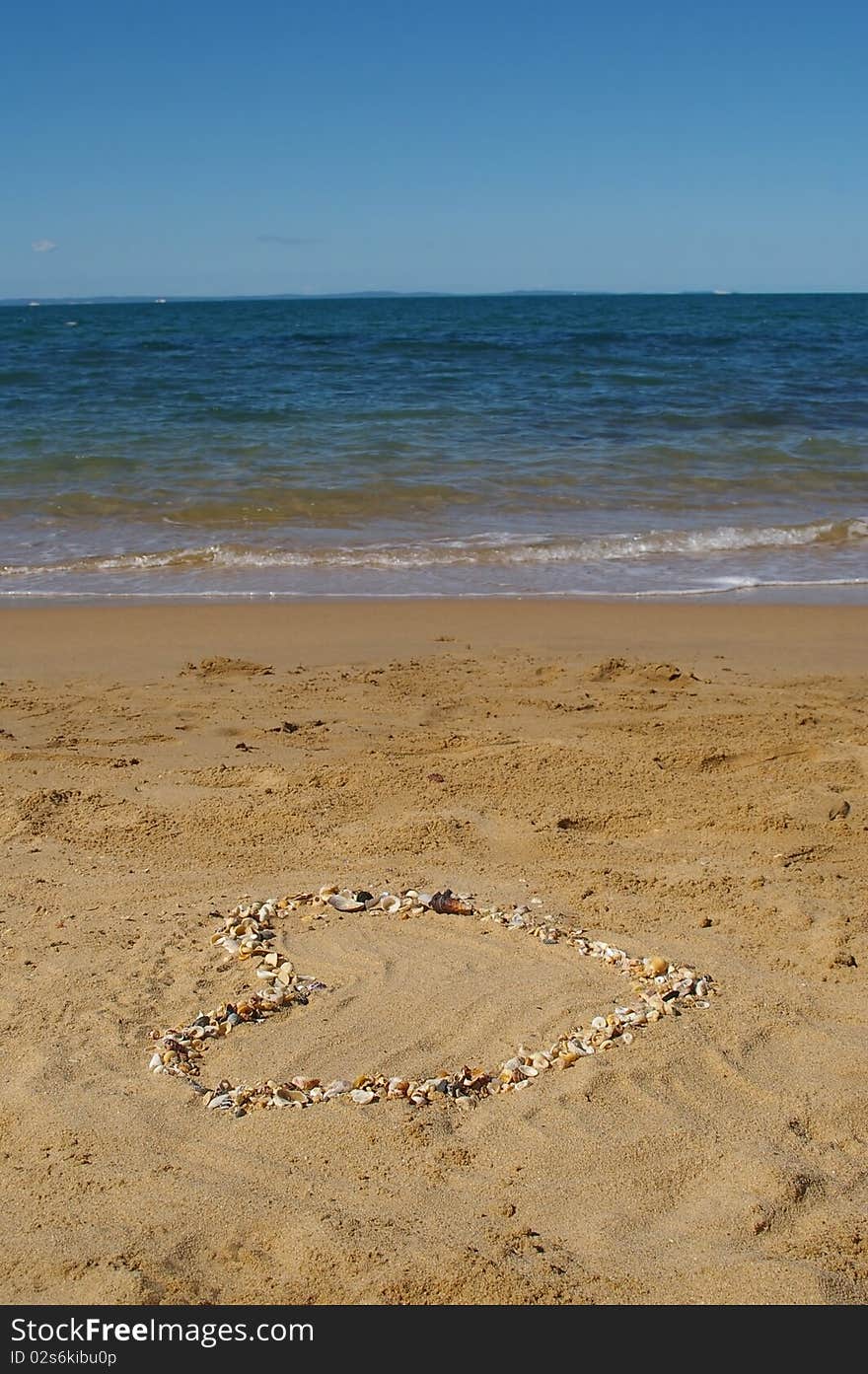 Love heart made of shells on beach background concept image. Love heart made of shells on beach background concept image