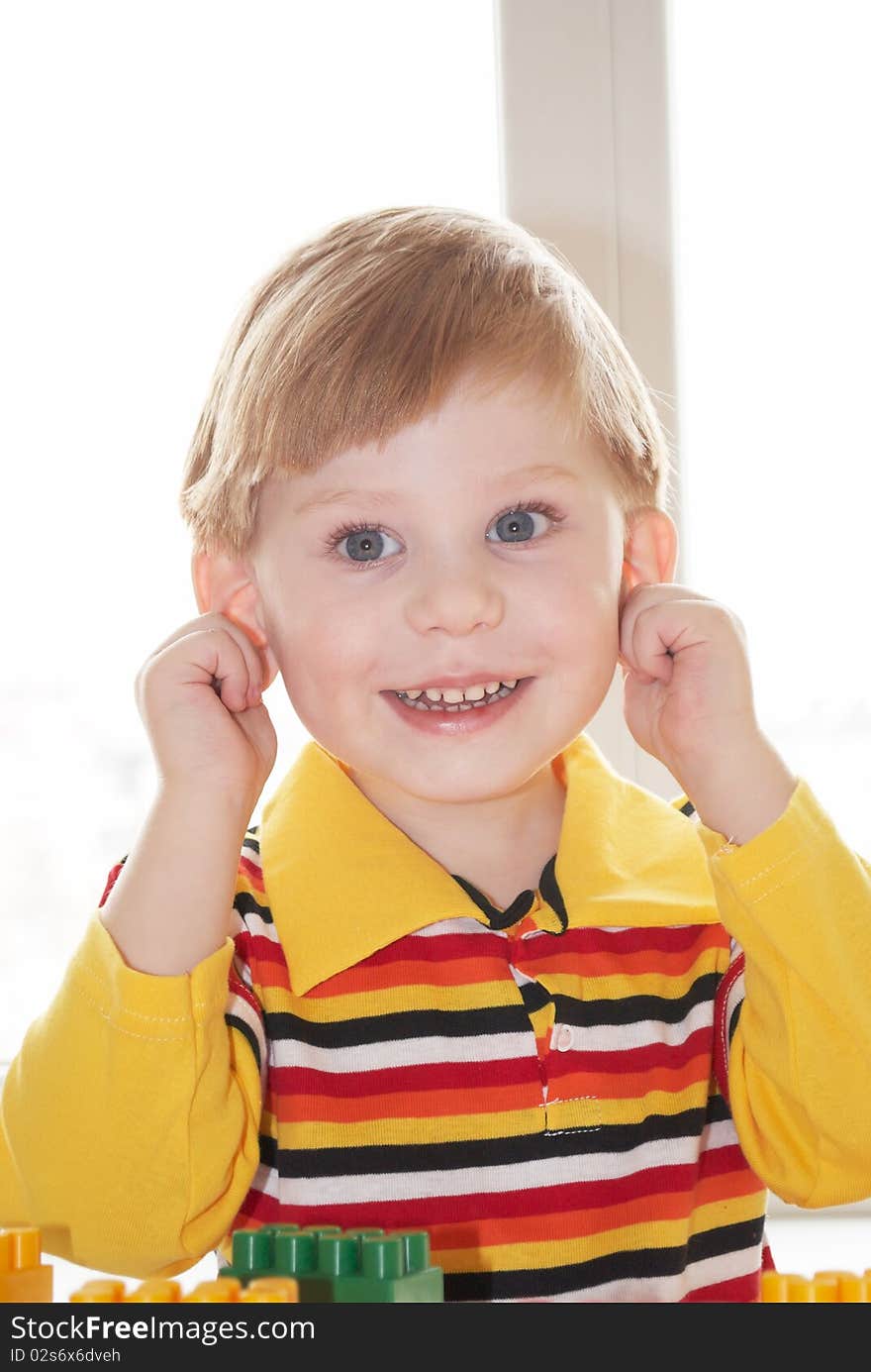 The beautiful little boy poses on a light background. The beautiful little boy poses on a light background