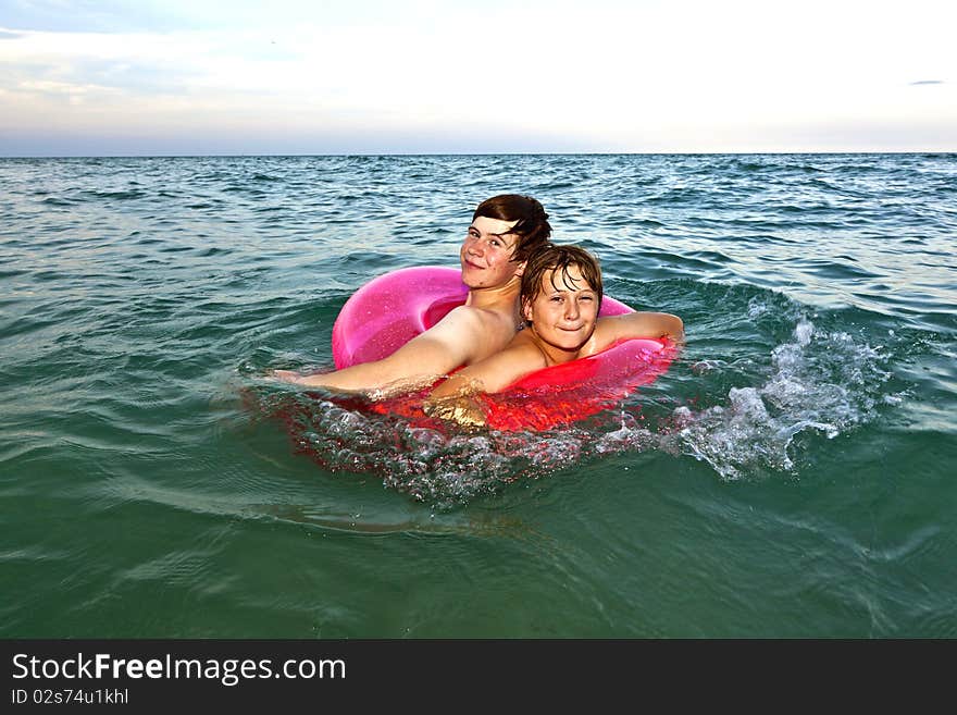 Two brothers in a swim ring have fun in the ocean