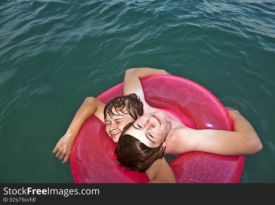 Two brothers in a swim ring have fun in the ocean