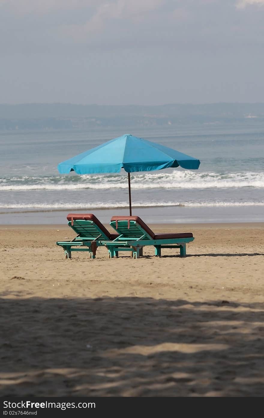 Two old chaise lounges with an umbrella stand on seacoast;. Two old chaise lounges with an umbrella stand on seacoast;