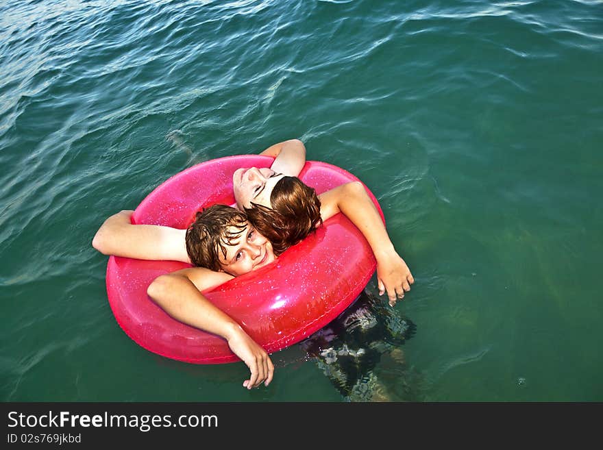 Two brothers in a swim ring have fun in the ocean