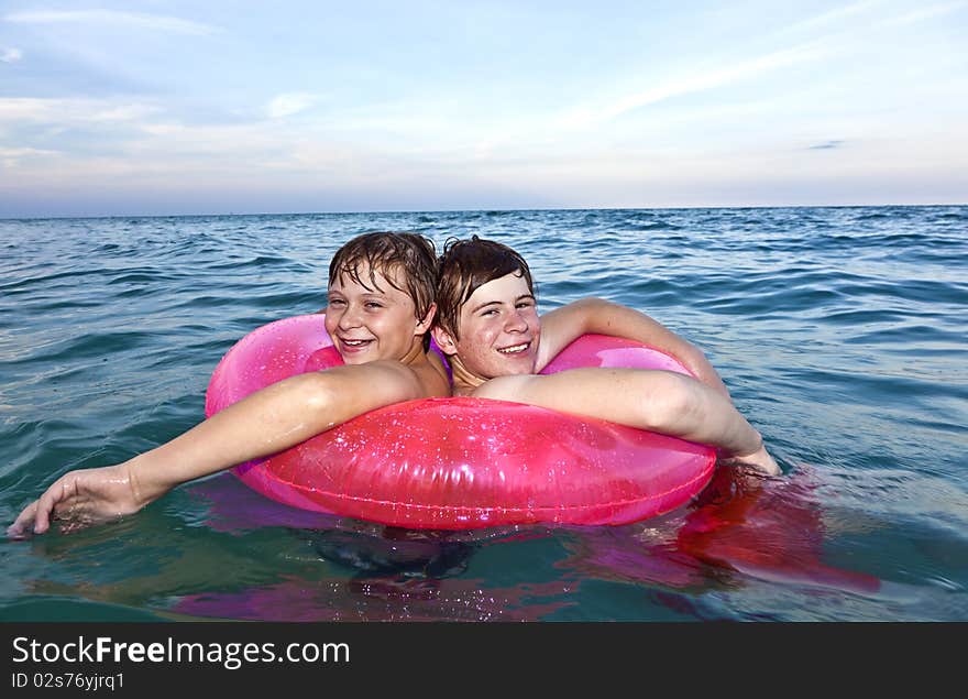 Two brothers in a swim ring have fun in the ocean