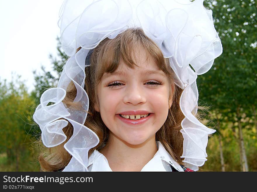 The laughing girl with white bows in the summer in park. The laughing girl with white bows in the summer in park